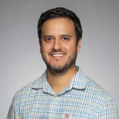 Headshot of Carlos Salazar on a gray background. 