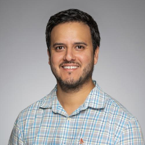 Headshot of Carlos Salazar on a gray background.