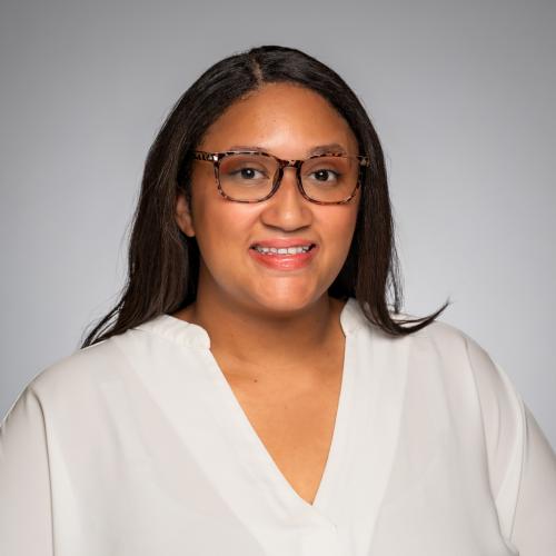 Headshot of Santana McGruder on a gray background. 