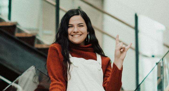Victoria Hart smiles and makes a hook 'em hand sign.